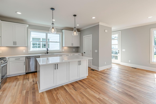 kitchen featuring appliances with stainless steel finishes, a center island, white cabinetry, and sink