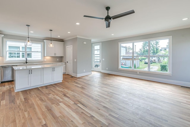 kitchen featuring pendant lighting, white cabinets, stainless steel dishwasher, ceiling fan, and ornamental molding