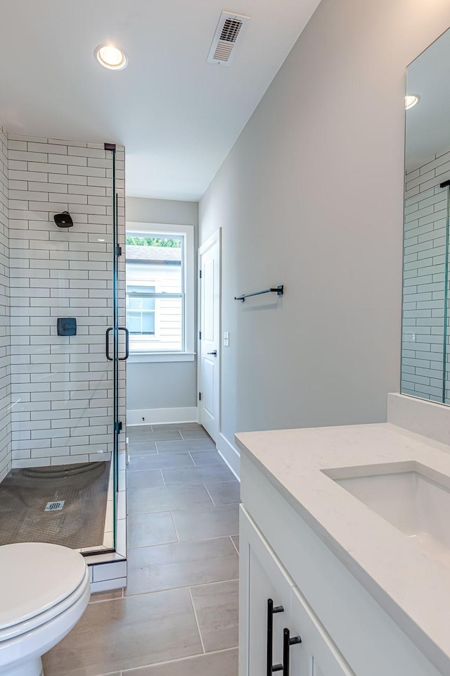 bathroom with toilet, vanity, tile patterned floors, and walk in shower