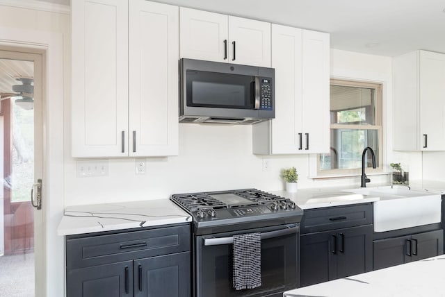 kitchen featuring white cabinetry, stainless steel appliances, light stone countertops, and sink