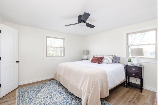 bedroom with ceiling fan, wood-type flooring, and multiple windows