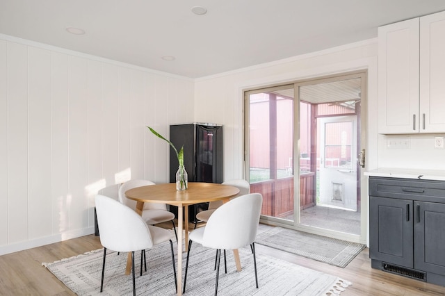 dining area featuring ornamental molding and light hardwood / wood-style flooring