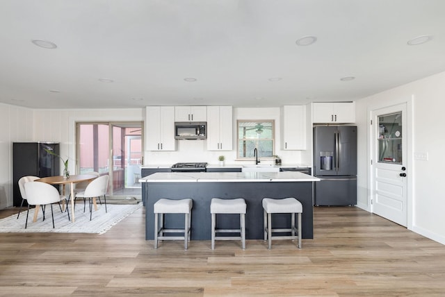 kitchen with white cabinetry, stainless steel appliances, a breakfast bar, and a kitchen island