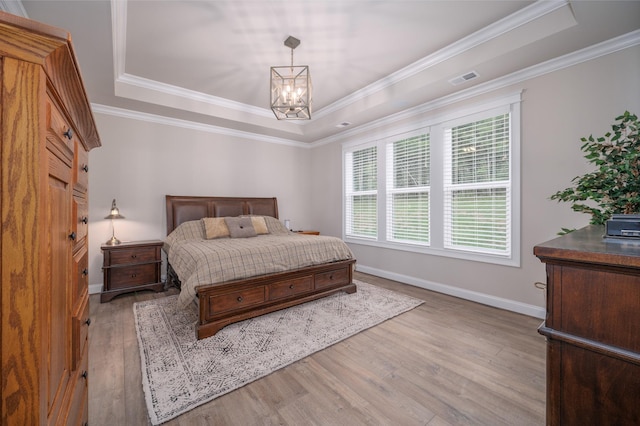 bedroom with an inviting chandelier, a raised ceiling, crown molding, and light hardwood / wood-style flooring