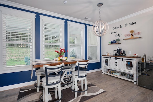 dining area featuring wood-type flooring, ornamental molding, and a chandelier