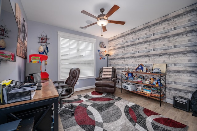 office space featuring ceiling fan, wood walls, and light wood-type flooring