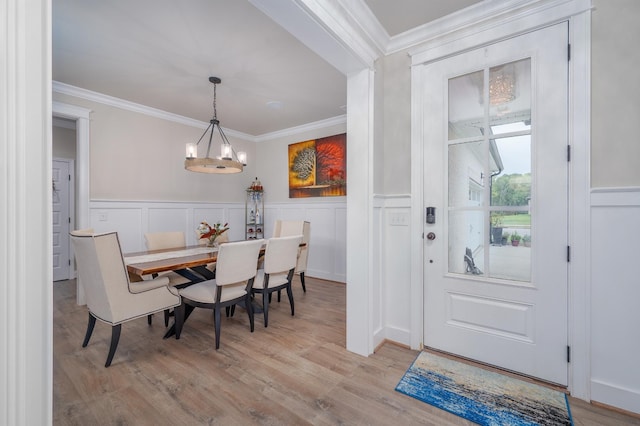 dining room with a notable chandelier, ornamental molding, and light hardwood / wood-style flooring