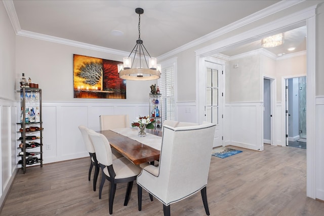 dining area featuring wood-type flooring, an inviting chandelier, and crown molding