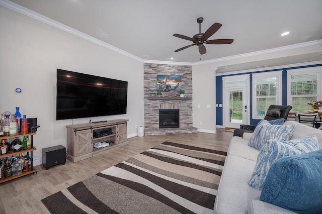 living room featuring a stone fireplace, ceiling fan, light hardwood / wood-style flooring, and crown molding