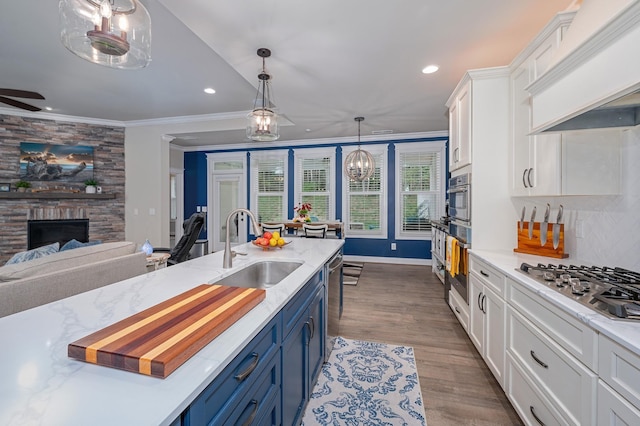 kitchen with white cabinetry, sink, blue cabinets, a fireplace, and custom range hood