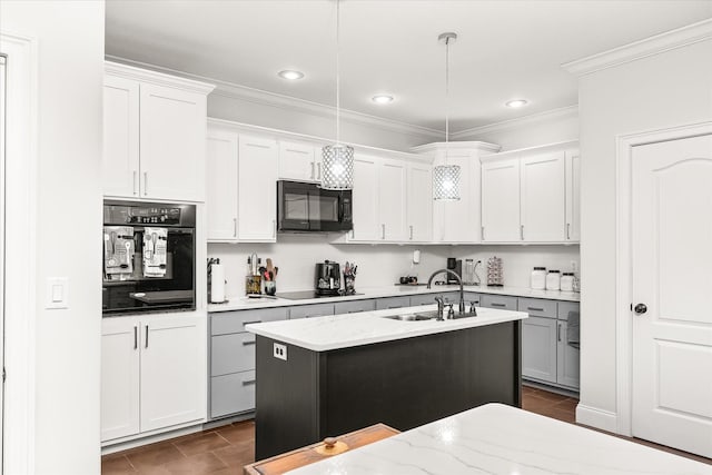 kitchen featuring pendant lighting, a kitchen island with sink, black appliances, sink, and white cabinetry