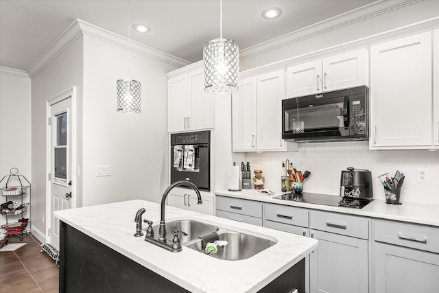 kitchen with black appliances, sink, hanging light fixtures, light stone counters, and white cabinetry