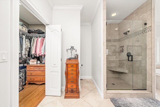 bathroom with tile patterned floors, crown molding, and a shower with door