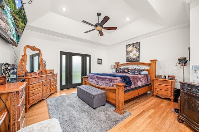 bedroom featuring a tray ceiling, light hardwood / wood-style flooring, ceiling fan, and ornamental molding