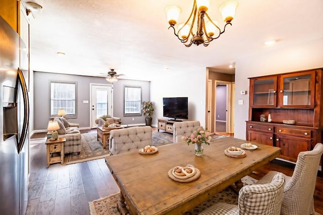 dining room with ceiling fan with notable chandelier and dark hardwood / wood-style flooring