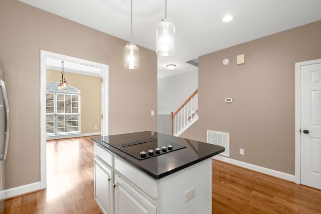 kitchen with a center island, black electric cooktop, decorative light fixtures, light hardwood / wood-style floors, and white cabinetry