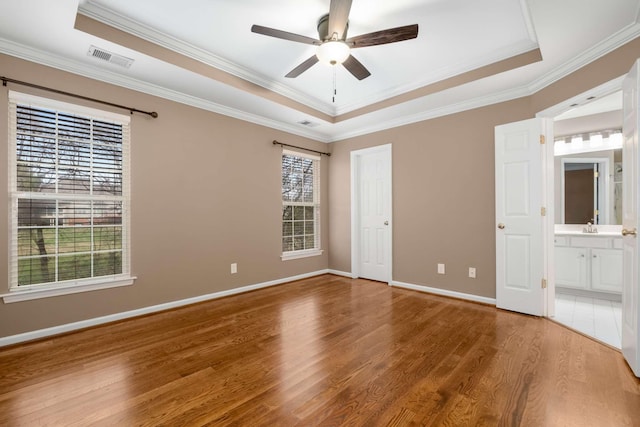 unfurnished bedroom featuring ceiling fan, connected bathroom, and a tray ceiling