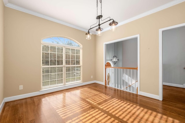 spare room with crown molding, a chandelier, and wood-type flooring