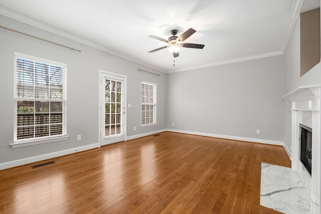 unfurnished living room featuring a premium fireplace, hardwood / wood-style floors, ceiling fan, and ornamental molding