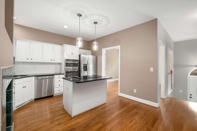 kitchen with a center island, hanging light fixtures, stainless steel appliances, tasteful backsplash, and white cabinets