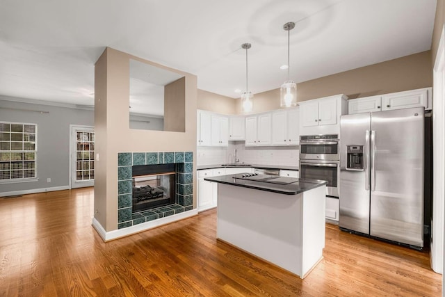 kitchen featuring appliances with stainless steel finishes, tasteful backsplash, sink, decorative light fixtures, and white cabinetry