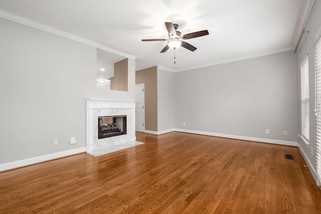 unfurnished living room with hardwood / wood-style floors, ceiling fan, ornamental molding, and a high end fireplace