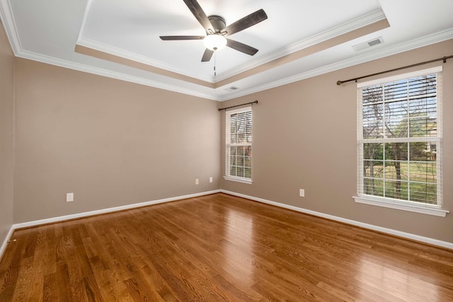 empty room featuring a tray ceiling, ceiling fan, ornamental molding, and hardwood / wood-style flooring