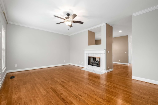 unfurnished living room featuring hardwood / wood-style flooring, ceiling fan, crown molding, and a premium fireplace