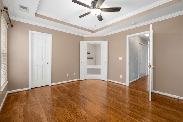 unfurnished bedroom with a tray ceiling, ceiling fan, crown molding, and hardwood / wood-style flooring