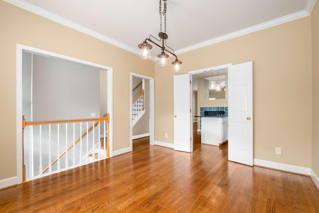 spare room featuring hardwood / wood-style flooring, a chandelier, and ornamental molding