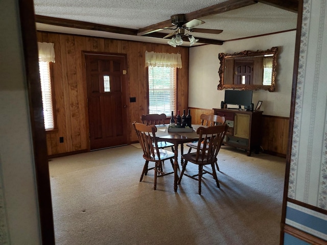 2055 Chisholm Rd, Iron City, TN 38463 - dining room with wooden walls, beamed ceiling, ceiling fan, a textured ceiling, and light colored carpet