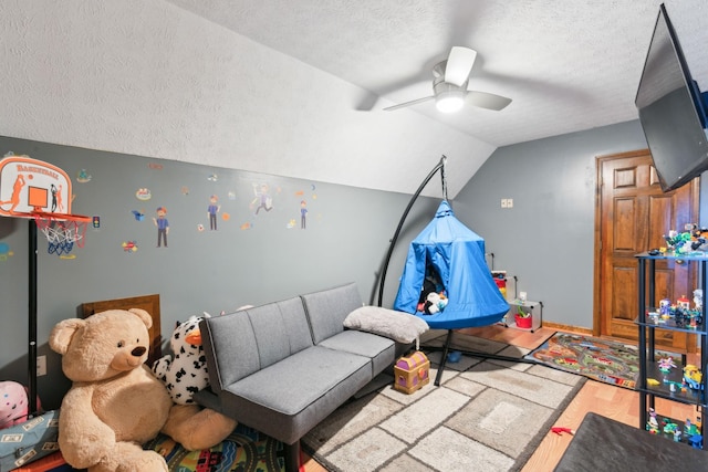 rec room featuring a textured ceiling, ceiling fan, lofted ceiling, and hardwood / wood-style flooring