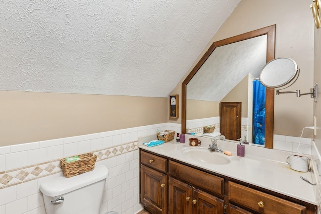 bathroom with tile walls, vanity, lofted ceiling, and toilet