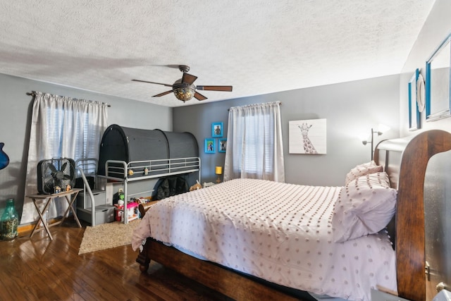 bedroom with multiple windows, a textured ceiling, ceiling fan, and dark wood-type flooring