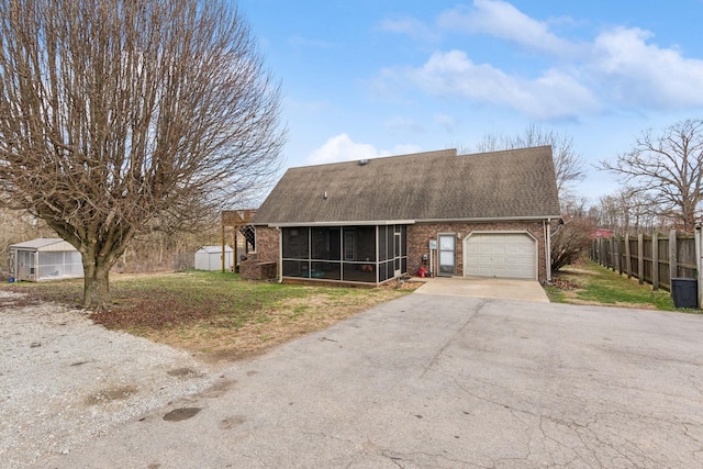 view of front facade featuring a sunroom, a shed, and a garage