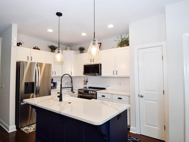 kitchen featuring hanging light fixtures, stainless steel appliances, light stone counters, an island with sink, and white cabinets