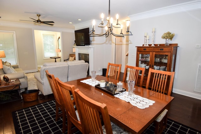 dining space featuring ceiling fan with notable chandelier, dark hardwood / wood-style floors, ornamental molding, and a fireplace