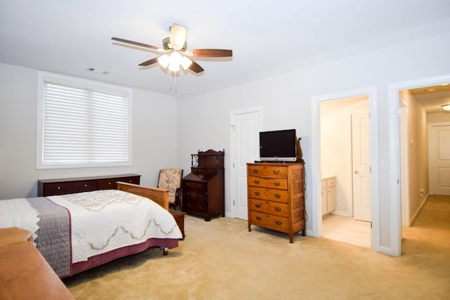 bedroom with ceiling fan, ensuite bathroom, and light carpet