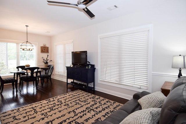 living room featuring dark hardwood / wood-style flooring and ceiling fan with notable chandelier