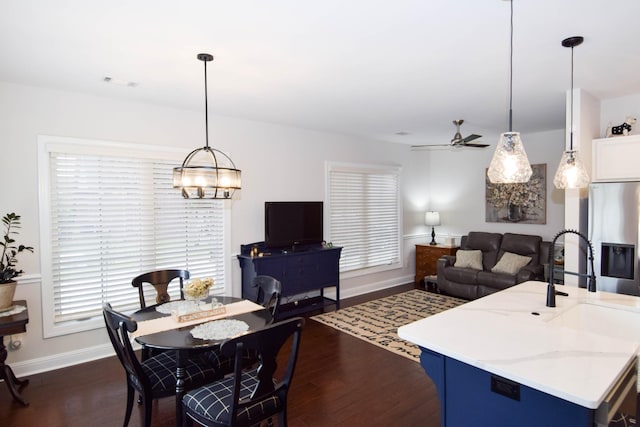 kitchen with a kitchen island with sink, hanging light fixtures, dark hardwood / wood-style floors, ceiling fan, and stainless steel fridge with ice dispenser