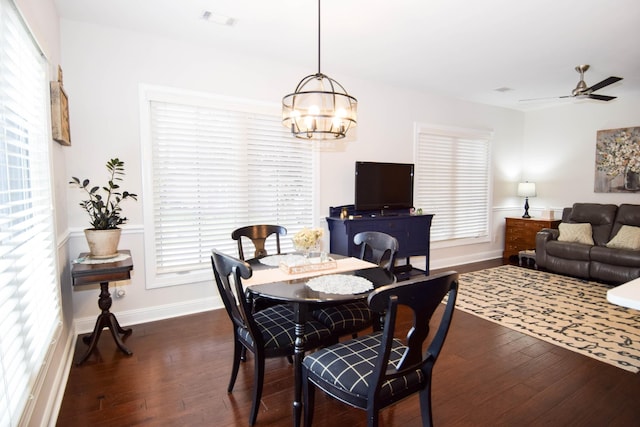 dining area with ceiling fan with notable chandelier and dark wood-type flooring