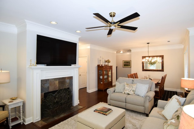 living room with a tiled fireplace, dark hardwood / wood-style flooring, ceiling fan with notable chandelier, and ornamental molding