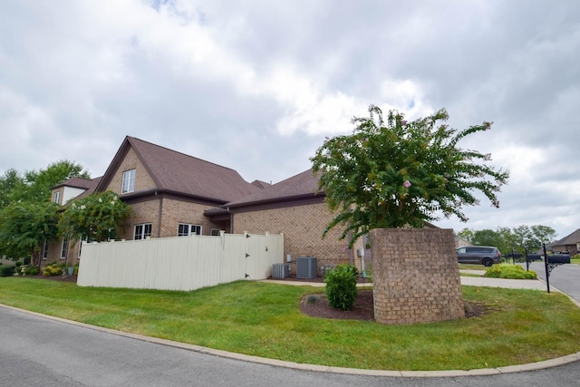 view of side of home featuring central AC unit and a lawn