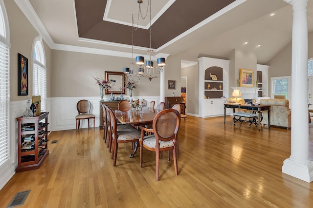 dining room with decorative columns, built in shelves, light hardwood / wood-style flooring, and a healthy amount of sunlight