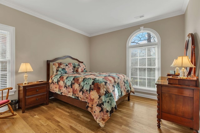 bedroom featuring light wood-type flooring, crown molding, and multiple windows