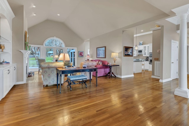 living room with high vaulted ceiling, light hardwood / wood-style flooring, and decorative columns