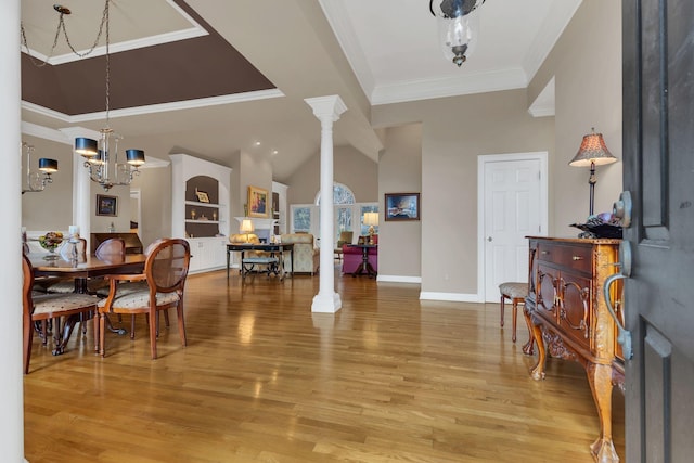 entrance foyer with hardwood / wood-style floors, an inviting chandelier, ornamental molding, a towering ceiling, and decorative columns