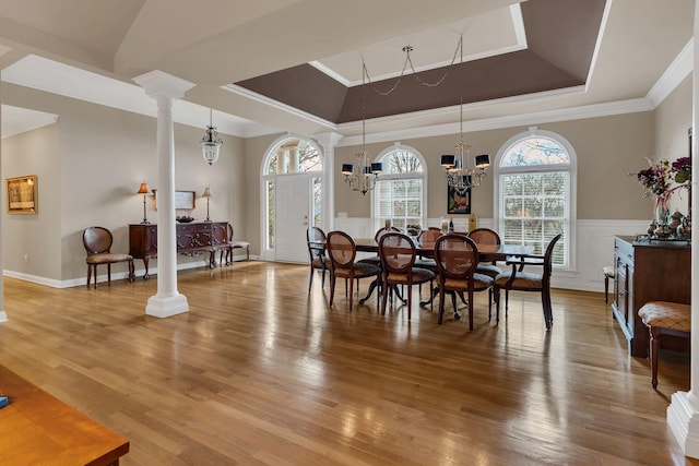 dining room featuring ornamental molding, a tray ceiling, ornate columns, and a notable chandelier