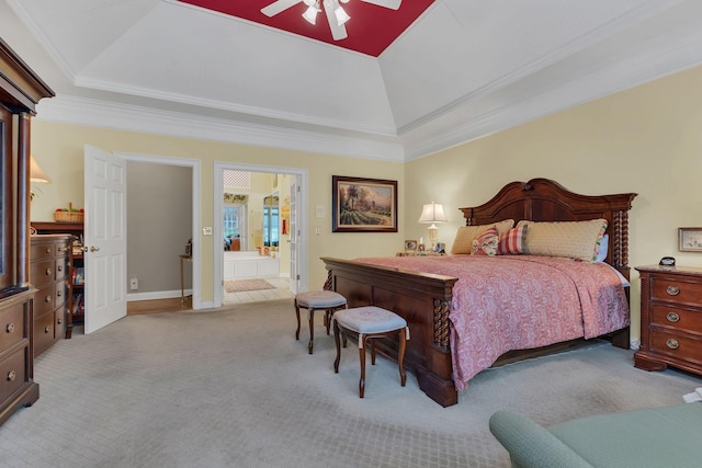 bedroom featuring ceiling fan, ornamental molding, connected bathroom, and a tray ceiling