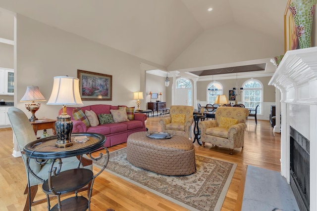 living room with a fireplace, high vaulted ceiling, and light hardwood / wood-style flooring